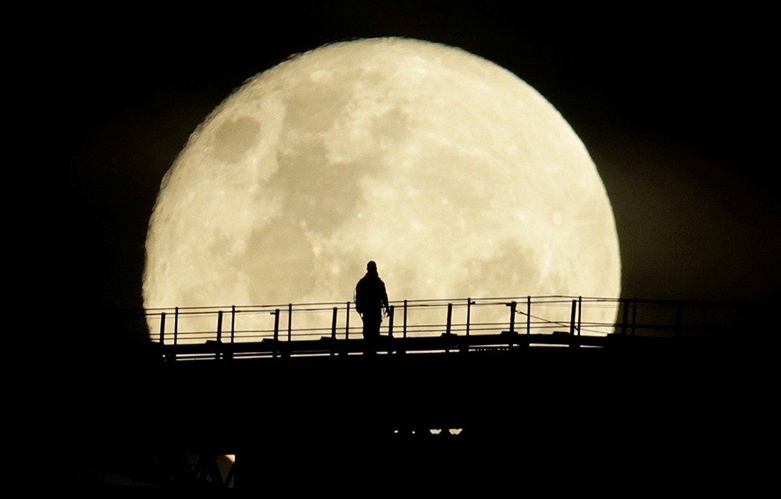 Homem caminha pela Ponte da Baía de Sydney durante fase final da Super Lua, vista da Austrália