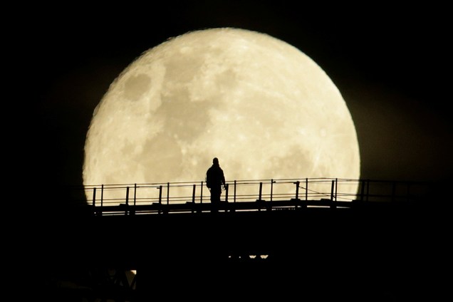Homem caminha pela Ponte da Baía de Sydney durante fase final da Super Lua, vista da Austrália - 15/11/2016