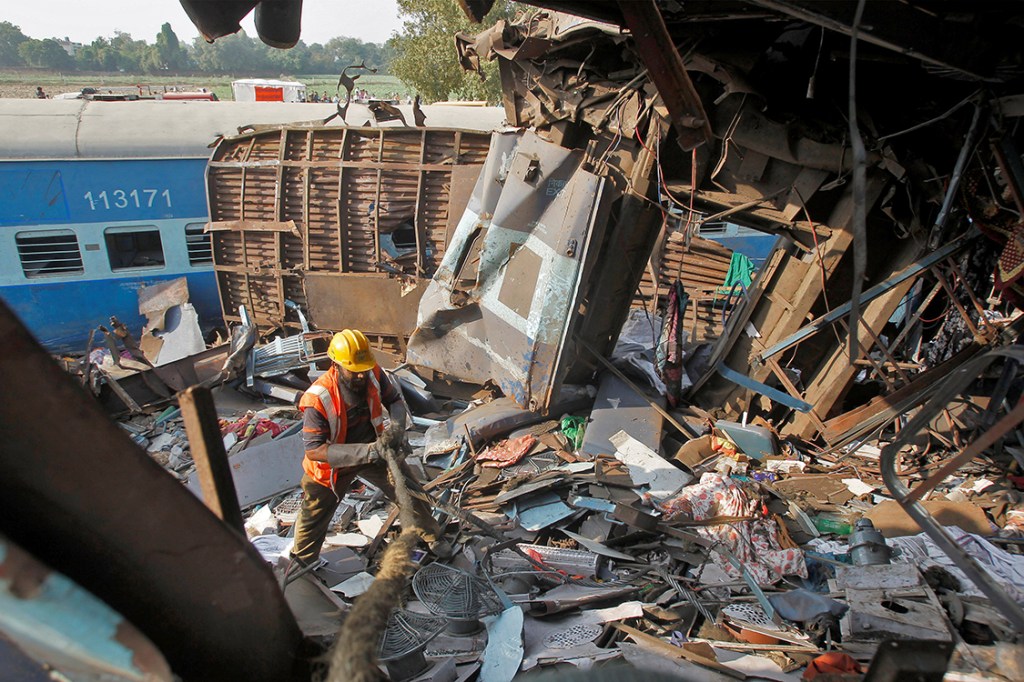 Membro do resgate retira escombros causados por trem descarrilhado na Índia