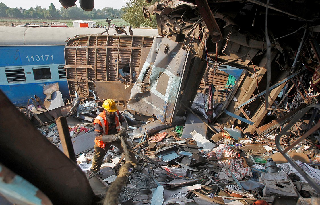 Membro do resgate retira escombros causados por trem descarrilhado na Índia