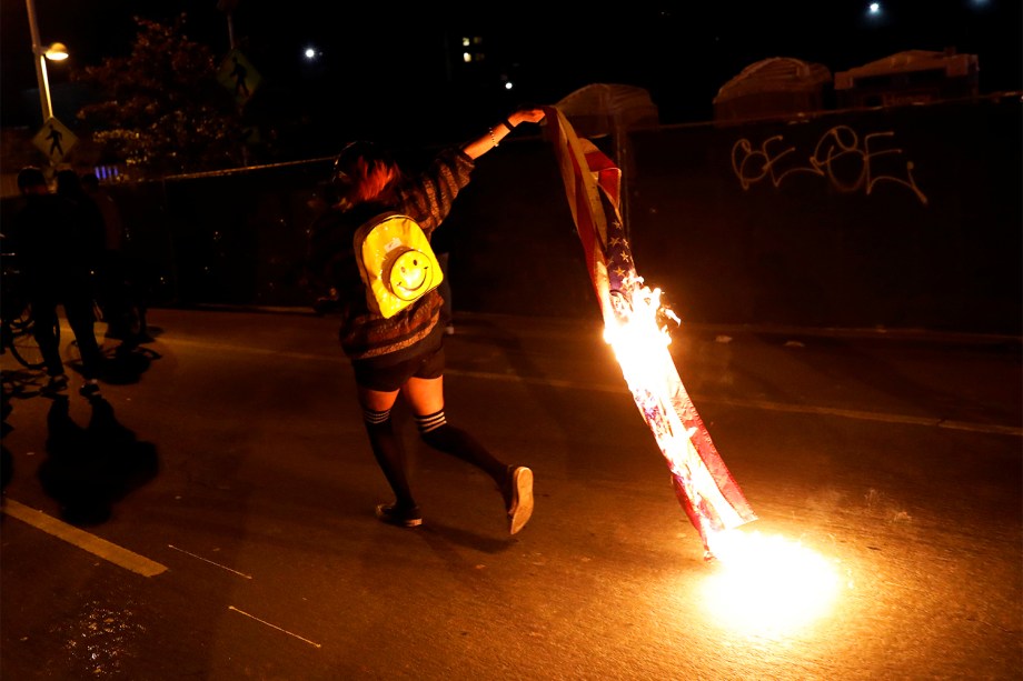 Manifestante queima bandeira dos Estados Unidos em protesto contra a vitória do republicano Donald Trump nas eleições presidenciais americanas, na cidade de Oakland, Califórnia - 10/11/2016
