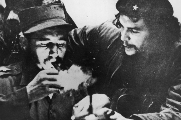 Fidel Castro acende seu charuto ao lado do argentino Che Guevara (1928-1967) durante os primeiros dias de sua campanha de guerrilha nas montanhas Sierra Maestra em Cuba, por volta de 1956