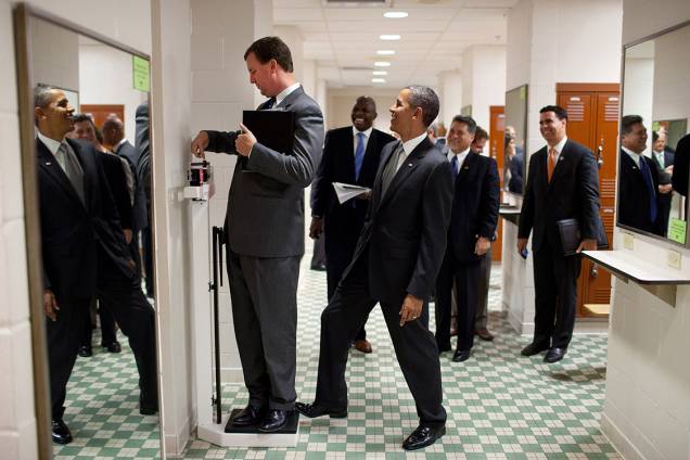 Obama coloca pé em balança enquanto diretor Marvin Nicholson mede seu peso em um vestiário durante visita à Universidade do Texas - 09/08/2010