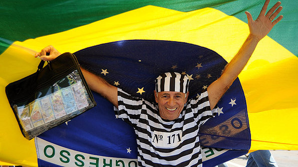 Um dos manifestantes de Brasília: com roupa de presidiário e mala de dinheiro (Foto:Pedro Ladeira/AFP)