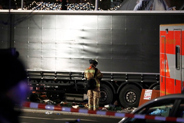 Bombeiro reza ao lado do caminhão que invadiu uma feira de Natal em Berlim, na Alemanha - 19/12/2016