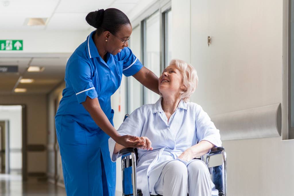 Senior Female Patient in Wheelchair & Nurse in Hospital