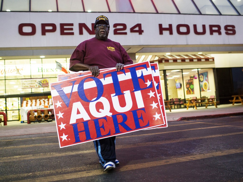 O voluntário Allie Green Jr. distribui placas para mostrar locais de votação nas primárias republicanas, em Austin, no Texas. Crédito: AP Photo/Tamir Kalifa