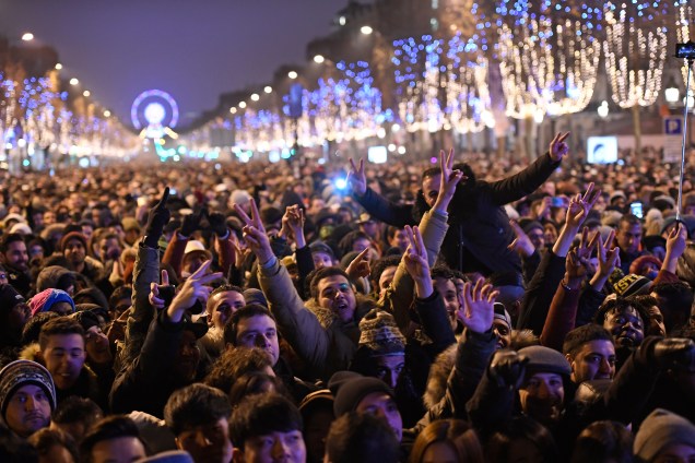 Público se reúne na avenida Champs-Elysees para assistir a um show de mapeamento de laser e vídeo 3D sobre o tema da candidatura de Paris para os Jogos Olímpicos de 2024, projetado no Arco do Triunfo como parte das comemorações de Ano Novo em Paris
