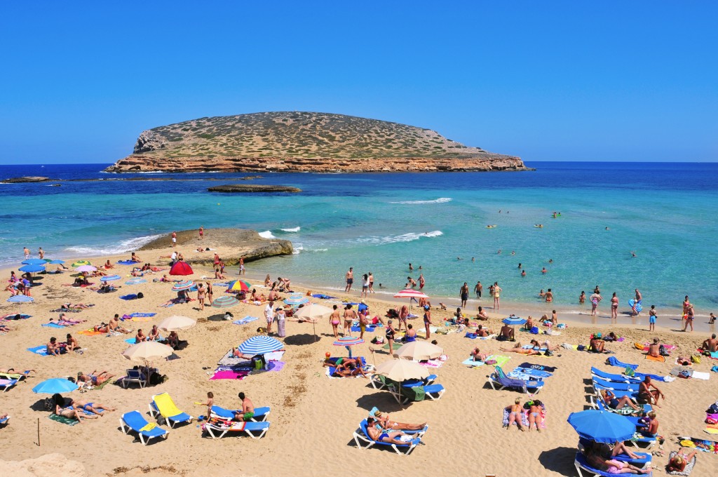 sunbathers at Cala Conta beach in San Antonio, Spain