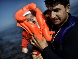 Homem segura um bebê ao chegam à ilha grega de Lesbos depois de atravessar o mar Egeu vindo da Turquia - 05/10/2015 (Aris Messinis/AFP)
