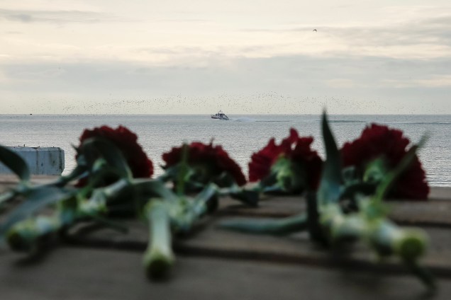 Flores são colocadas em um cais enquanto um barco do Ministério de Emergências russo, realiza buscas perto do local do acidente com um avião militar que caiu no Mar Negro - 26/12/2016