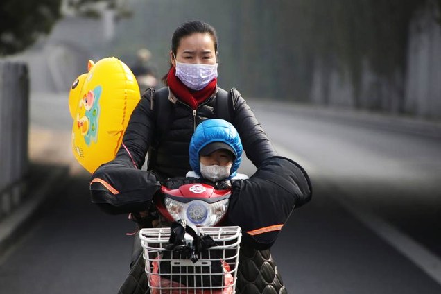 Mulher e seu filho usam máscaras contra a poluição durante a hora do rush matutino em Pequim, na China -
