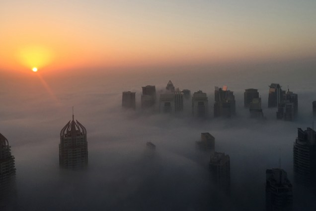 O sol se levanta atrás dos arranha-céus durante uma manhã nevoenta em Dubai, nos Emirados Árabes - 05/12/2016