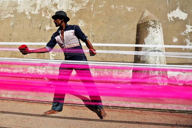 Trabalhador pinta cordas em uma estrada de Ahmedabad, na Índia - 15/12/2016