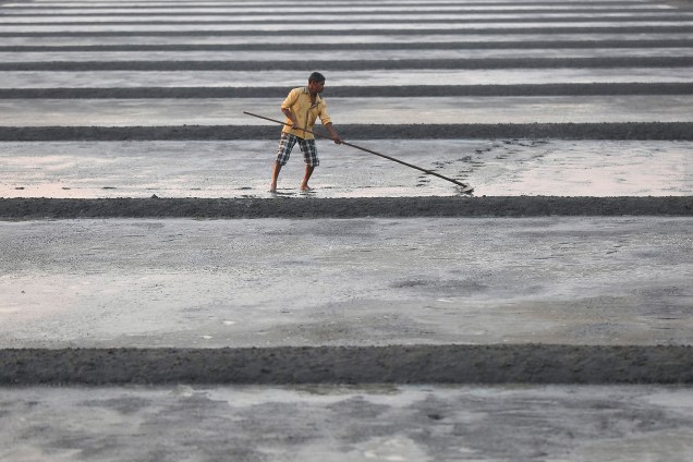 Trabalhador nivela uma mina de sal em Mumbai, na Índia - 09/12/2016