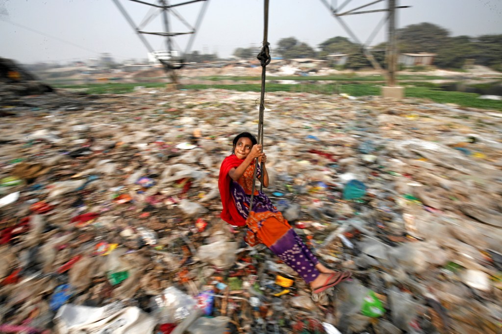 Menina brinca em um lixão em Bangladesh
