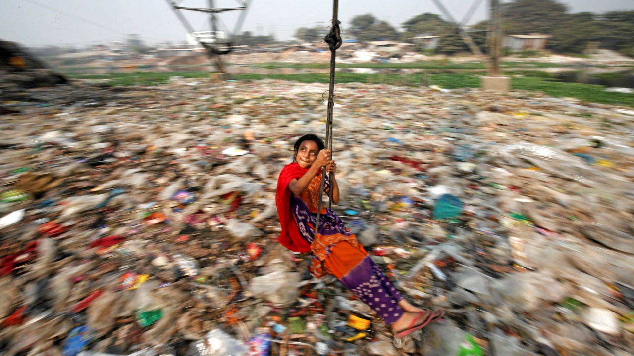 Menina brinca em um lixão em Bangladesh