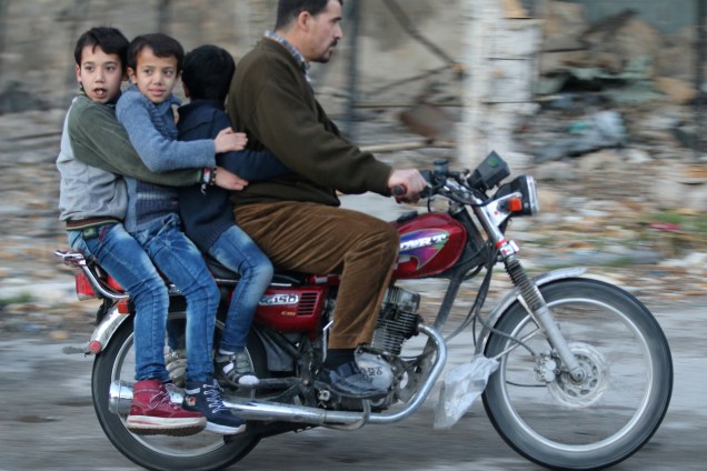 Crianças montam uma motocicleta em um bairro rebelde da cidade de Alepo, na Síria - 02/12/2016