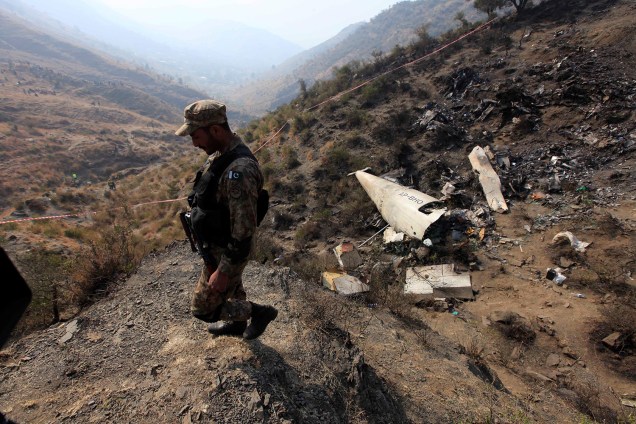 Soldado paquistanês patrulha a área onde caiu um avião da Pakistan International Airline, próximo à região de Abbotabad, no Paquistão - 08/12/2016