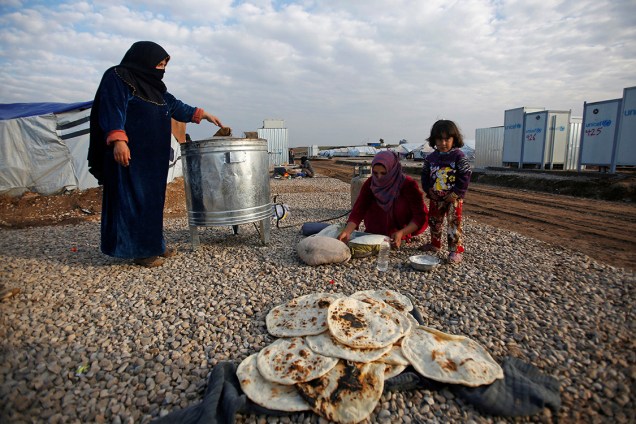 Mulheres refugiadas que escaparam de Mosul, cidade tomada pelo Estado Islâmico, preparam pão no acampamento onde foram instaladas no leste do Iraque - 27/12/2016