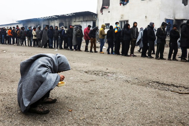Migrantes fazem fila para receber alimentos, em um aduaneiro abandonado de Belgrado, na Sérvia - 22/12/2016