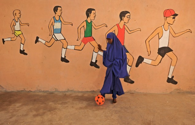 Garota joga bola em frente ao muro de seu colégio em Mogadício, capital da Somália - 06/12/2016