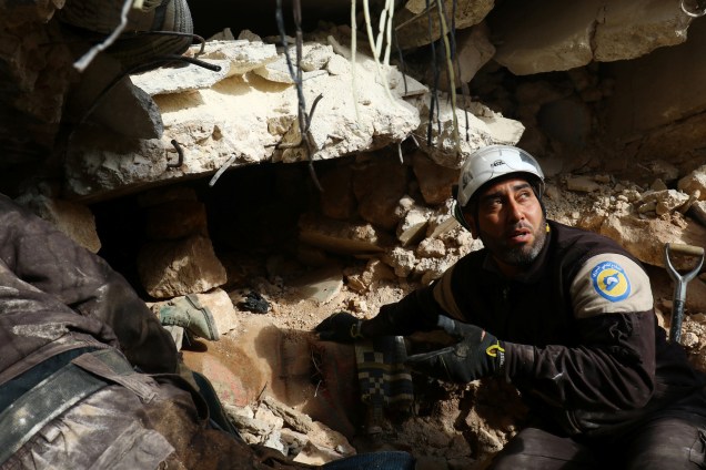 Membro da Defesa Civil procura por sobreviventes sob os escombros de um edifício atingido por ataques aéreos na cidade de Idlib, na Síria - 05/12/2016