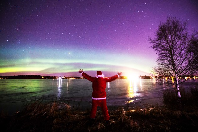 Um homem vestido de Papai Noel observa a <em>aurora boreal</em> em Vaasa, na Finlândia - 24/12/2016