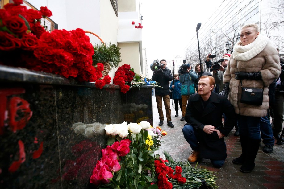 Pessoas depositam flores no edifício do conjunto de Alexandrov (Coro do Exército Vermelho), em homenagem às vítimas do coral que estavam no avião militar russo que caiu neste domingo (25)