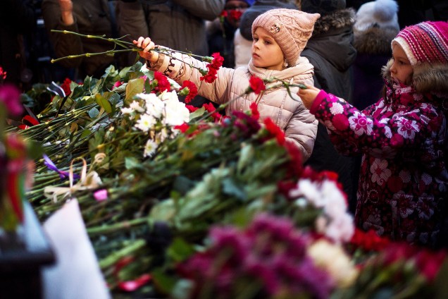 Crianças depositam flores no edifício do conjunto de Alexandrov (Coro do Exército Vermelho), em homenagem às vítimas do coral que estavam no avião militar russo que caiu neste domingo (25)