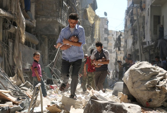 Homens carregam bebês em meio aos escombros, após  ataque aéreo em destruir edifícios em Alepo, na Síria - 11/09/2016