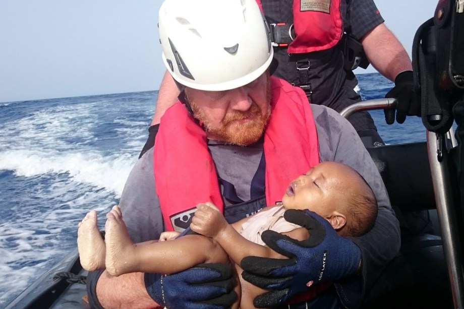 Socorrista alemão da organização humanitária Sea-Watch segura o corpo de um bebê afogado, resgatado após naufrágio de uma embarcação com imigrantes na costa da Líbia