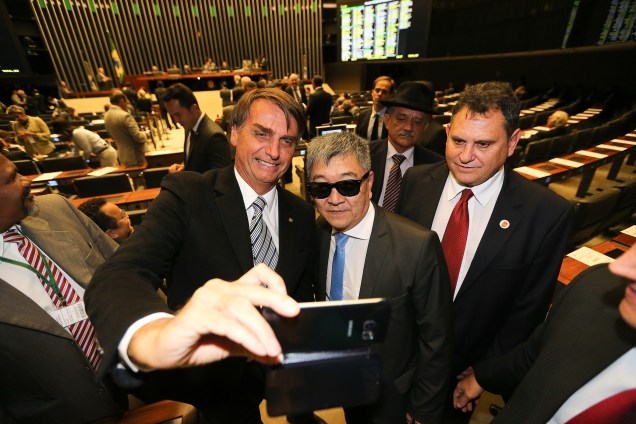 O deputado Jair Bolsonaro faz selfie com o agente da polícia federal Newton Ishii durante visita do policial ao plenário da Câmara dos Deputados, em Brasília (DF)