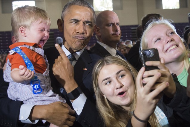 O presidente dos Estados Unidos, Barack Obama, tenta alegrar o pequeno Brooks Breitwieser de dez meses ao tirar uma selfie durante evento de campanha de Hillary Clinton, em Columbus, Ohio