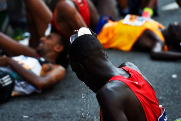 Participante se refresca após cruzar a linha de chegada da 92ª Corrida de São Silvestre. Ao fundo, atletas descansam - 31/12/2016