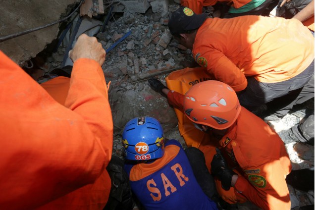Socorristas tentam resgatar pessoas soterradas após o terremoto na Indonésia
