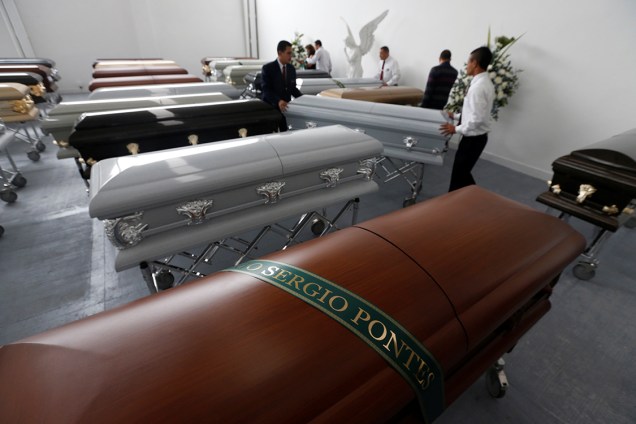 Funeral workers arrange coffins near the coffin holding the remains of former soccer player and sports commentator Mario Sergio Pontes who died along with others in an accident of the plane that crashed into the Colombian jungle with Brazilian soccer team Chapecoense onboard, in Medellin, Colombia December 1, 2016. REUTERS/Jaime Saldarriaga