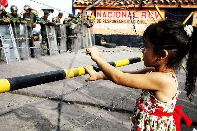Menina observa guardas da Venezuela  próximo a ponte internacional Francisco de Paula Santander, que liga Urena, na Venezuela, e Cúcuta, na Colômbia - 18/12/2016