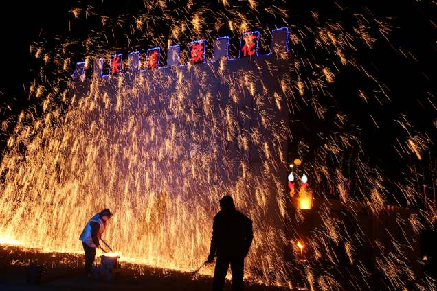 Homens atiram ferro derretido em uma parede durante as festividades do ano novo chinês, na China Homens atiram ferro derretido em uma parede durante as festividades do ano novo chinês, na China