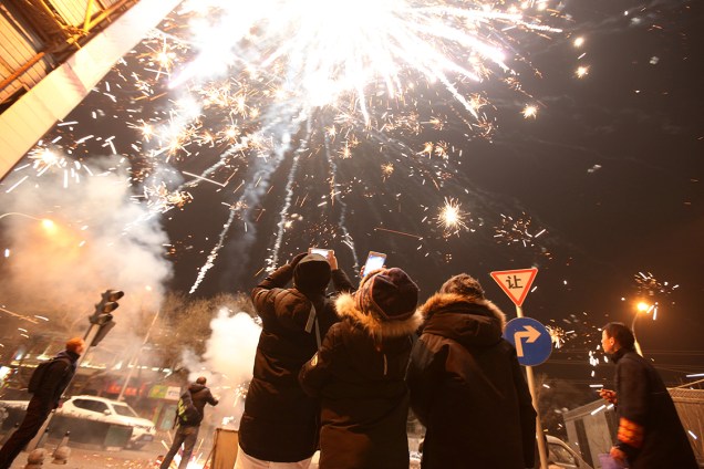 Pessoas assistem à exibição de fogos de artifício durante as festividades do ano novo chinês, na China