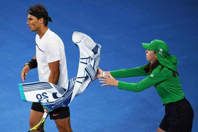 A ball girl catches Spain's Rafael Nadal's towel in his game against Canada's Milos Raonic during their men's singles quarter-final match on day ten of the Australian Open tennis tournament in Melbourne on January 25, 2017.  / AFP PHOTO / Greg Wood / IMAGE RESTRICTED TO EDITORIAL USE - STRICTLY NO COMMERCIAL USE