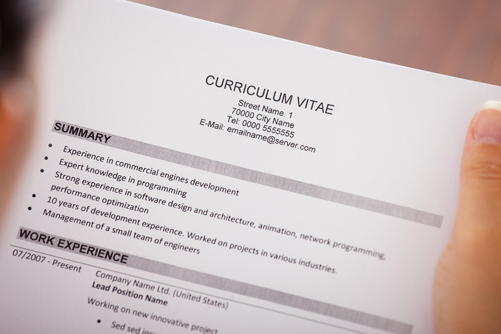 Close-up Of Young Businesswoman Reading Curriculum Vitae At Desk