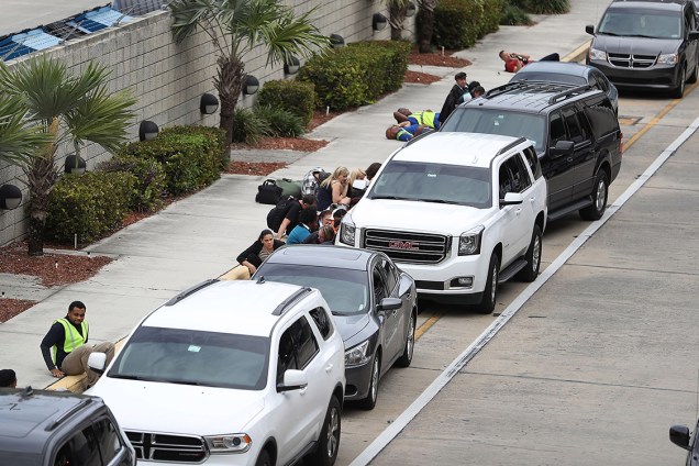 Pessoas se escondem atrás de carros estacionados após atirador matar cinco no aeroporto internacional de Fort Lauderdale, na Flórida - 06/01/2017