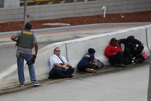 Pessoas se escondem atrás de construção de concreto após atirador abrir fogo e matar cinco no aeroporto internacional de Fort Lauderdale, na Flórida - 06/01/2017