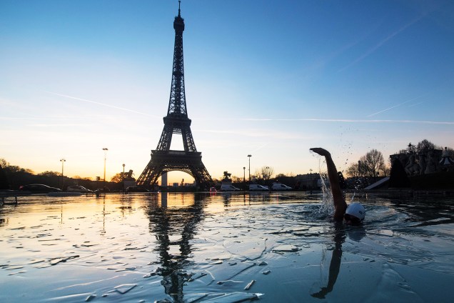 Homem nada em água congelada do Jardins du Trocadéro, parque localizado em frente à Torre Eiffel, em Paris, na França - 06/01/2017