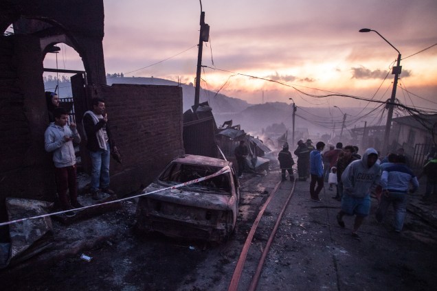 Pessoas trabalham para extinguir as chamas em uma casa em Valparaiso, no Chile