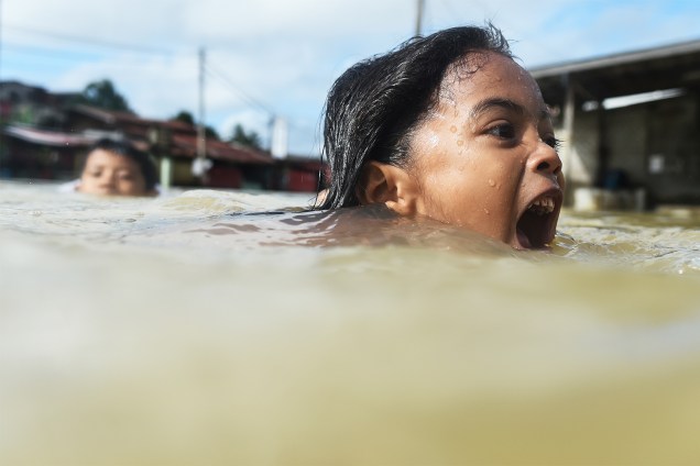 Crianças nadam em rua inundada no nordeste de Rantau Panjang, na Malásia - 05/01/2017