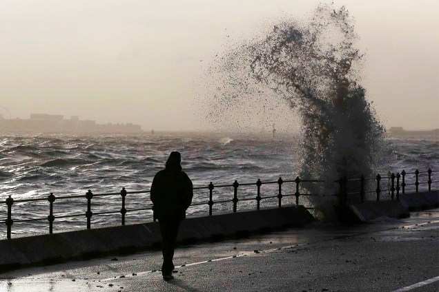 Homem caminha próximo de ondas em New Brighton, no norte da Inglaterra - 11/01/2017