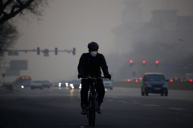 Ciclista usa uma máscara enquanto pedala em uma avenida em meio a uma densa camada de poluição em Pequim, na China - 03/01/2017