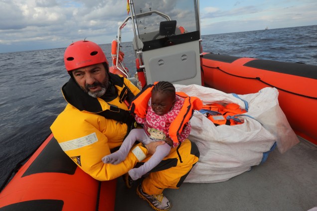 Oscar Camps, fundador da ONG espanhola Proactiva Open Arms, segura uma criança resgatada de um bote superlotado de imigrantes no Mar Mediterrâneo, na costa da Líbia - 02/01/2017